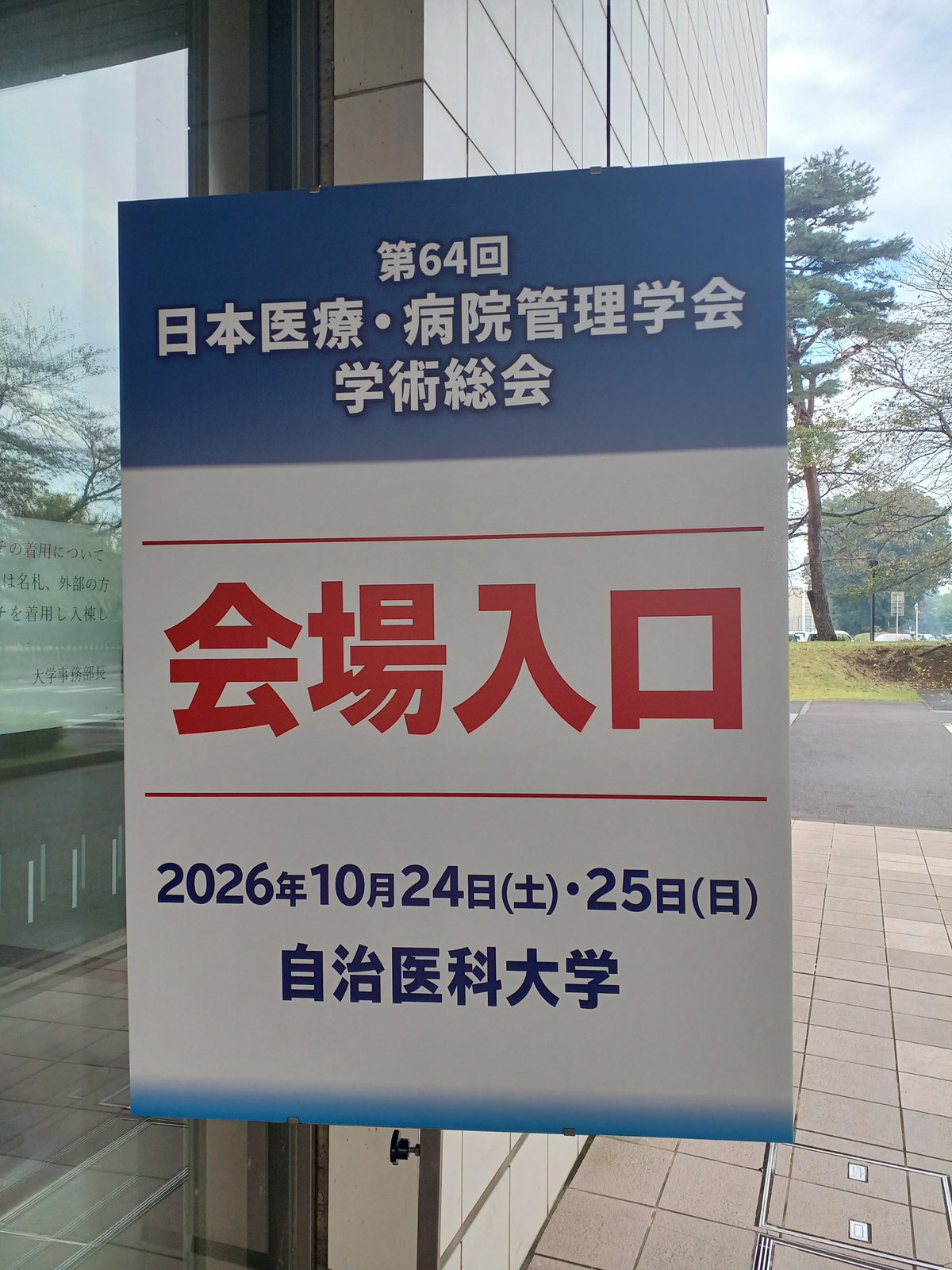 第64回日本医療・病院管理学会学術総会の会場入口の看板(2026年10月24日・25日、自治医科大学)